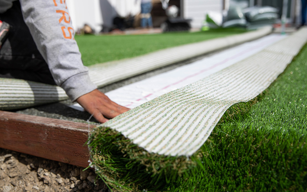 Image of a contractor installing artificial grass with seam tape and glue to secure it